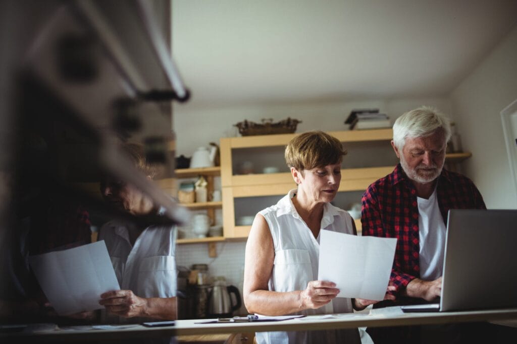 Should You Ditch That Old With-Profits Policy Before You Retire? 5 Midlife couple reviewing paperwork together at their kitchen table